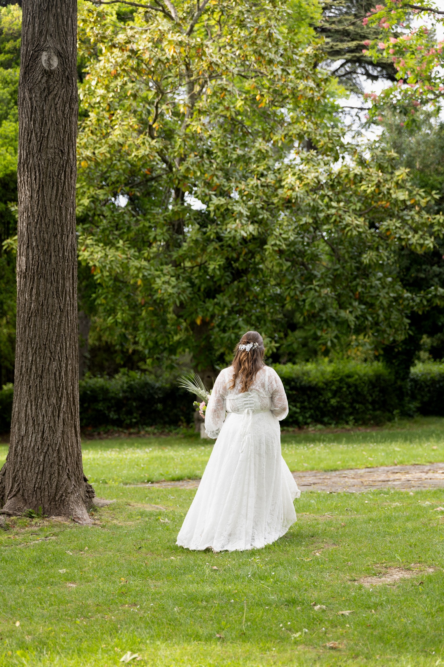 La mariée, de dos, marche sur la pelouse d'un parc