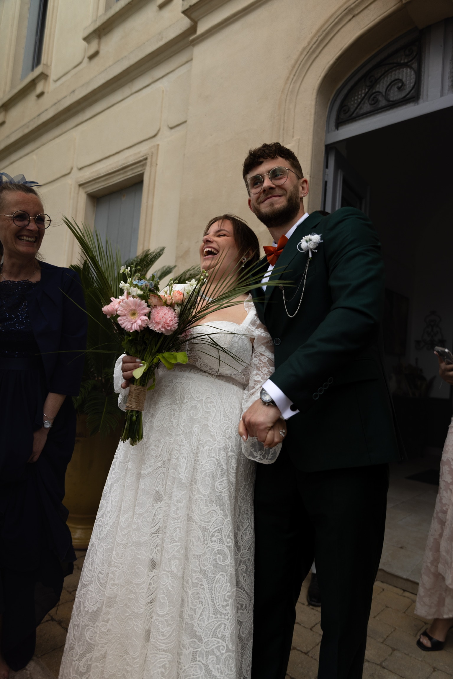 La mariée rit aux éclats, bouquet à la main, aux côtés du marié
