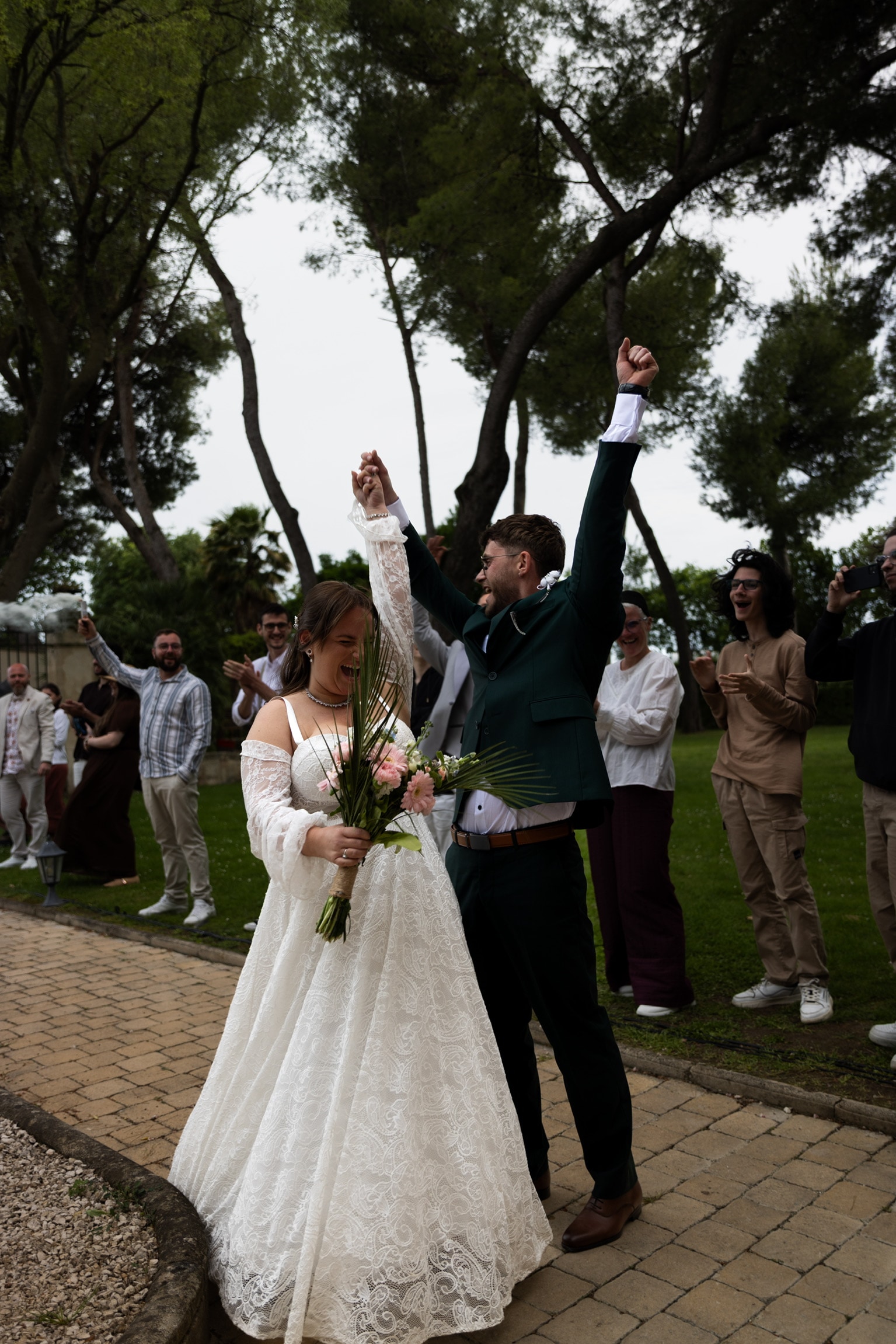 Le marié lève le bras et les invités acclament le couple dehors