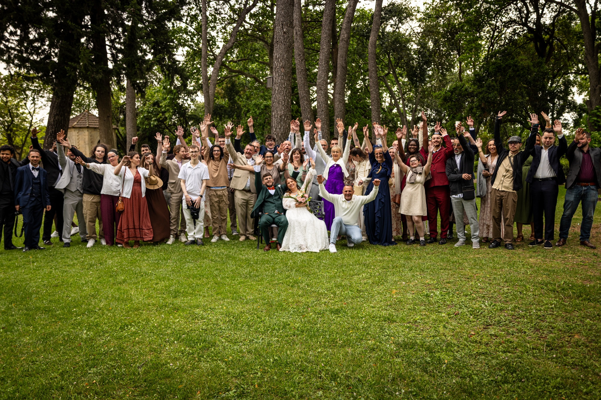 Photo de groupe des invités autour des mariés, bras levés