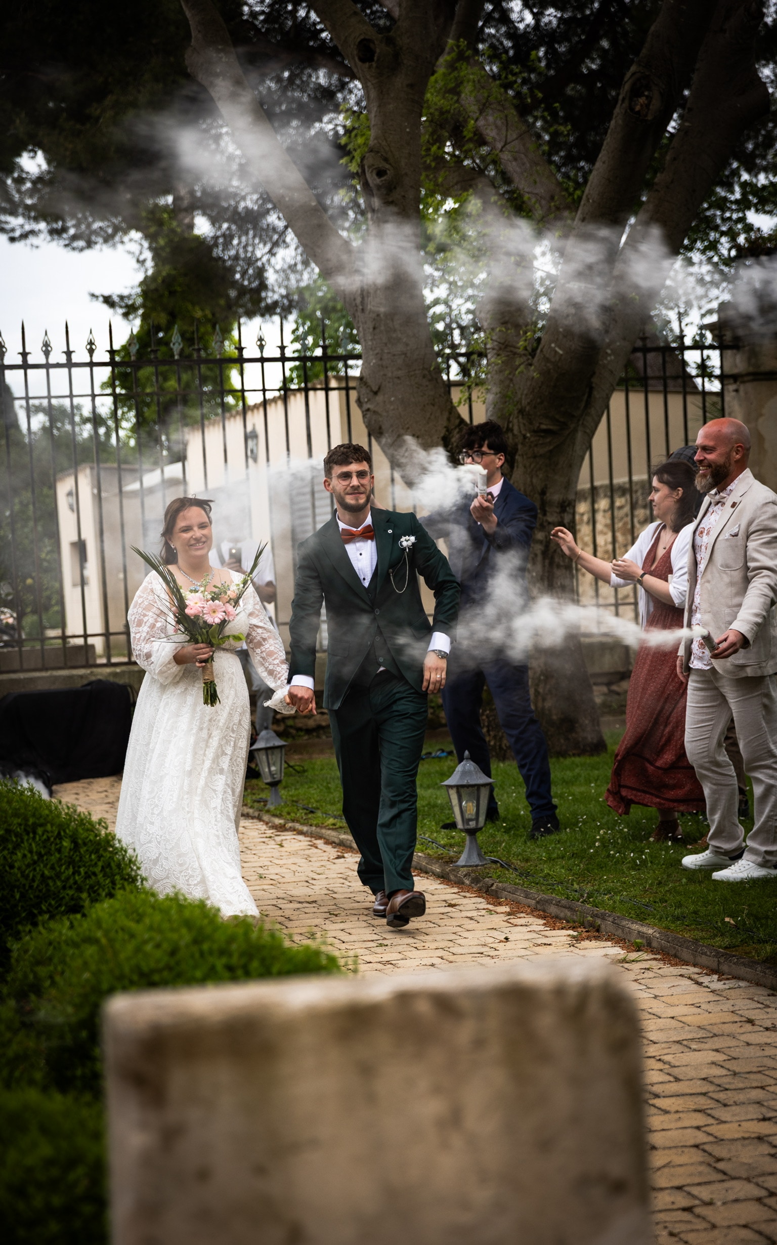 Les mariés avancent dans l'allée au milieu de la fumée, entourés d'invités