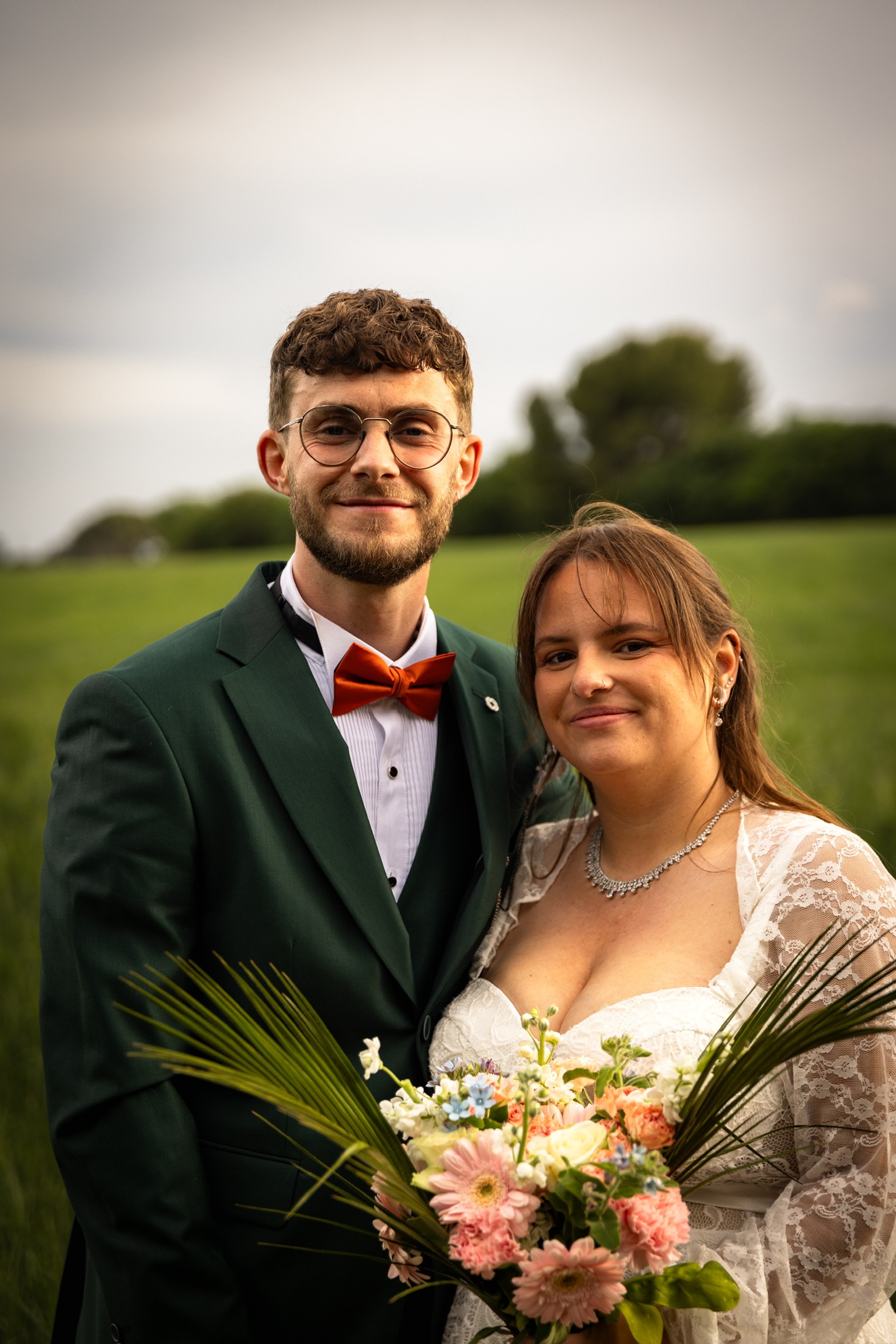 Portrait des mariés souriants devant un champ