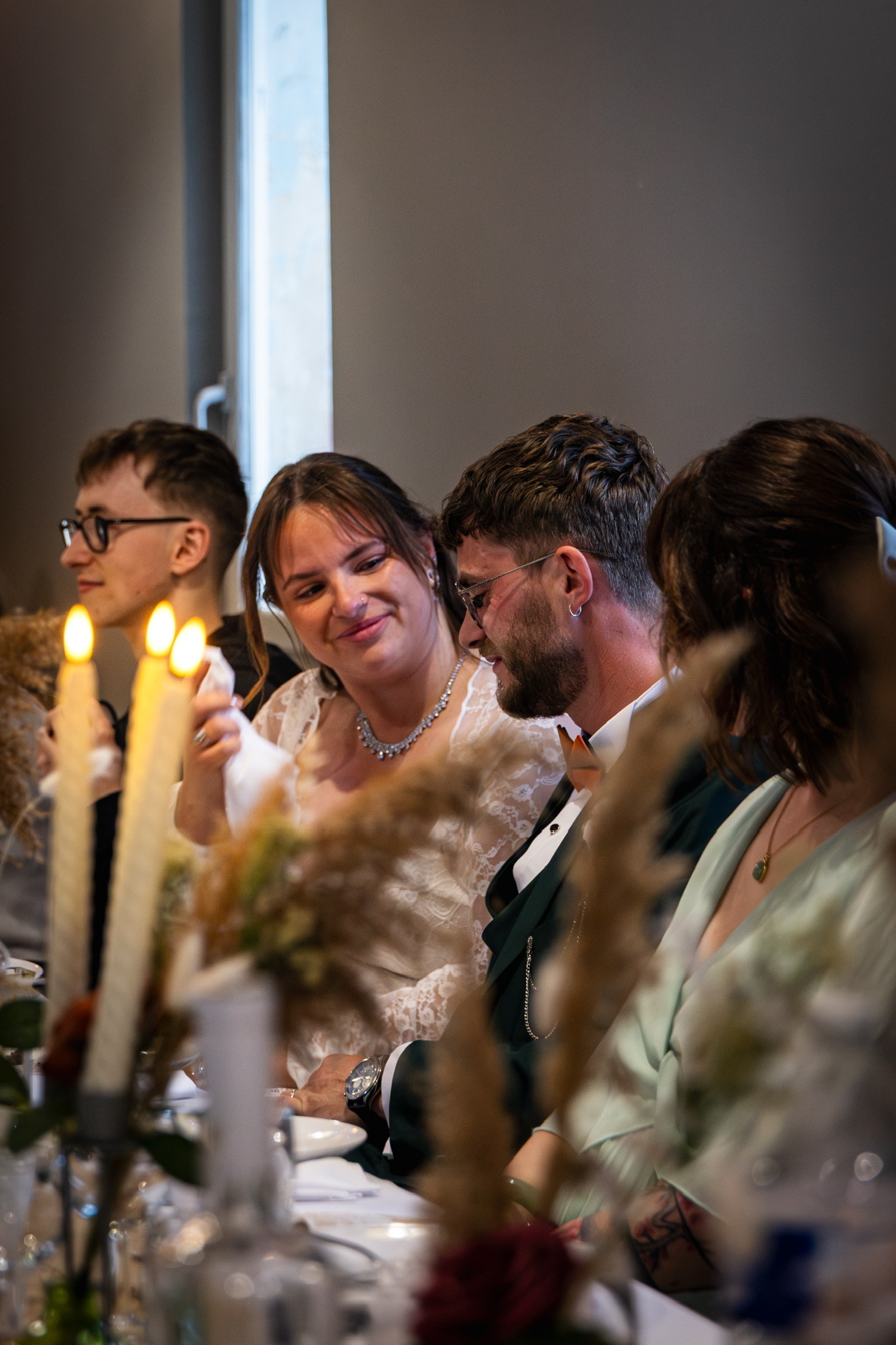 Invités souriants autour de la table du repas, bougies au premier plan
