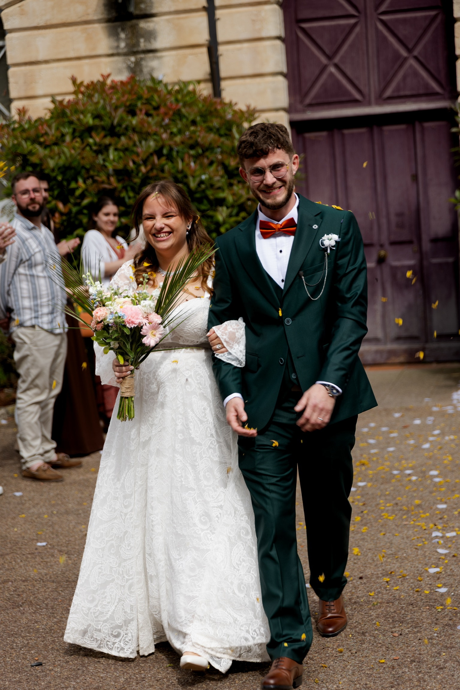 La mariée rit en sortant, sous une pluie de pétales